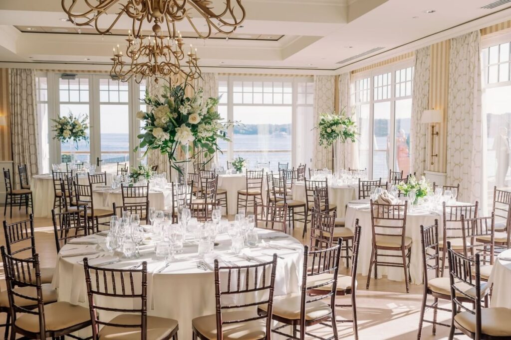 Interior wedding reception setup at Beauport Hotel in Gloucester Massachusetts featuring elegant dinner tables, coastal-inspired décor, and warm lighting in a modern waterfront ballroom.