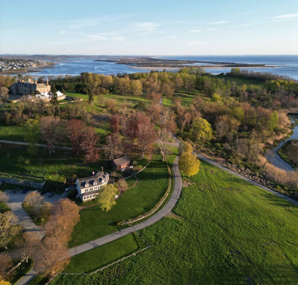 Drone view of Crane Estate in Ipswich Massachusetts showing the grand seaside mansion, expansive green lawn, and Atlantic Ocean coastline on the North Shore.