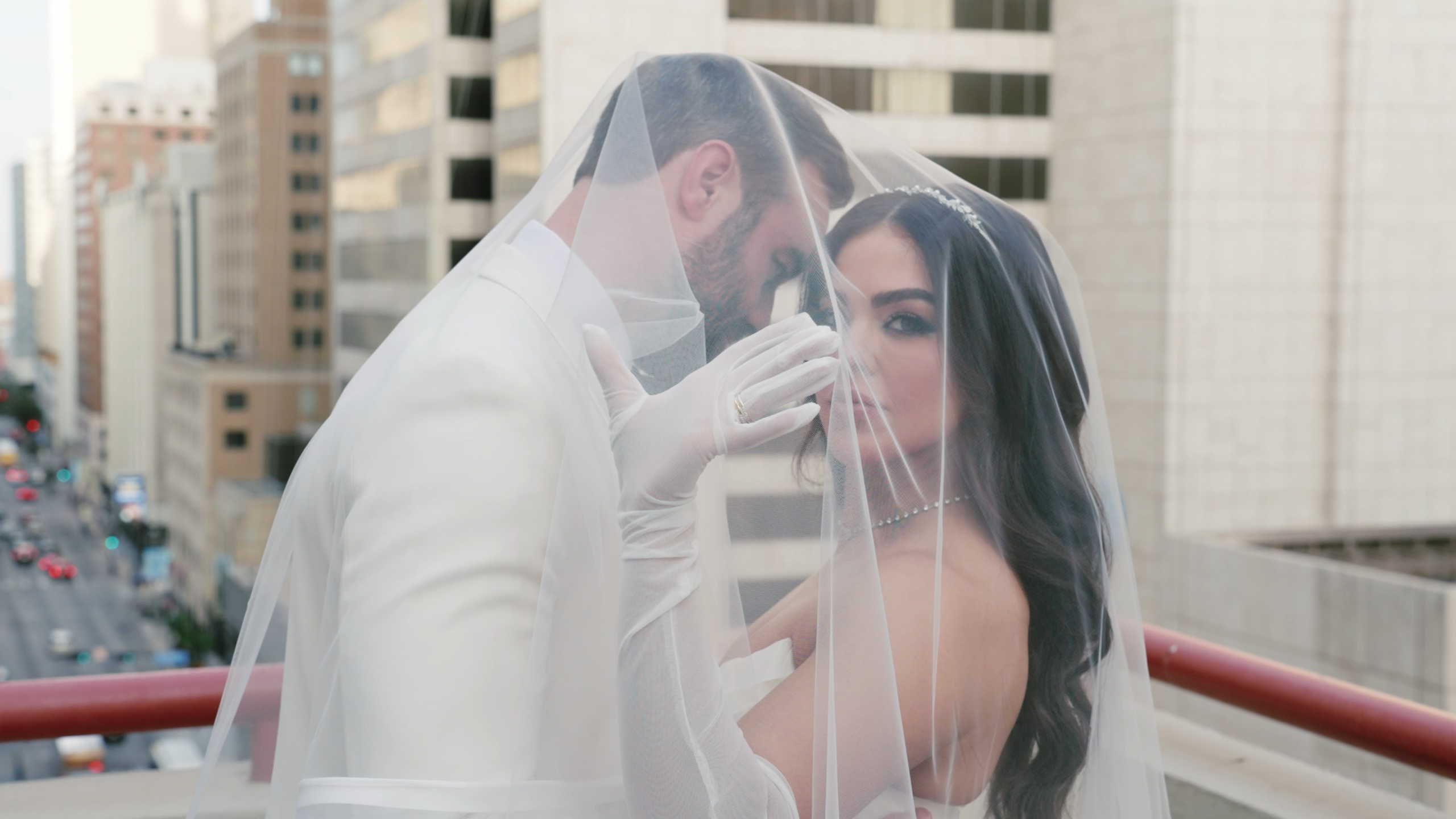 Bride and groom atop a wedding location in Boston with the bride's veil covering them both in this romantic shot.