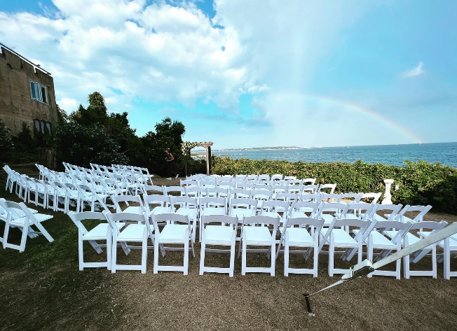 Exterior wedding ceremony at Hammond Castle Museum in Gloucester Massachusetts overlooking the ocean with historic stone architecture and coastal water views on the North Shore.