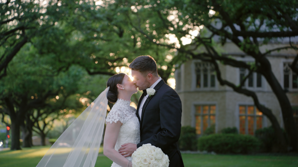 Bride and groom kissing in front of a beautiful Dallas venue as the sun sets in the distance.