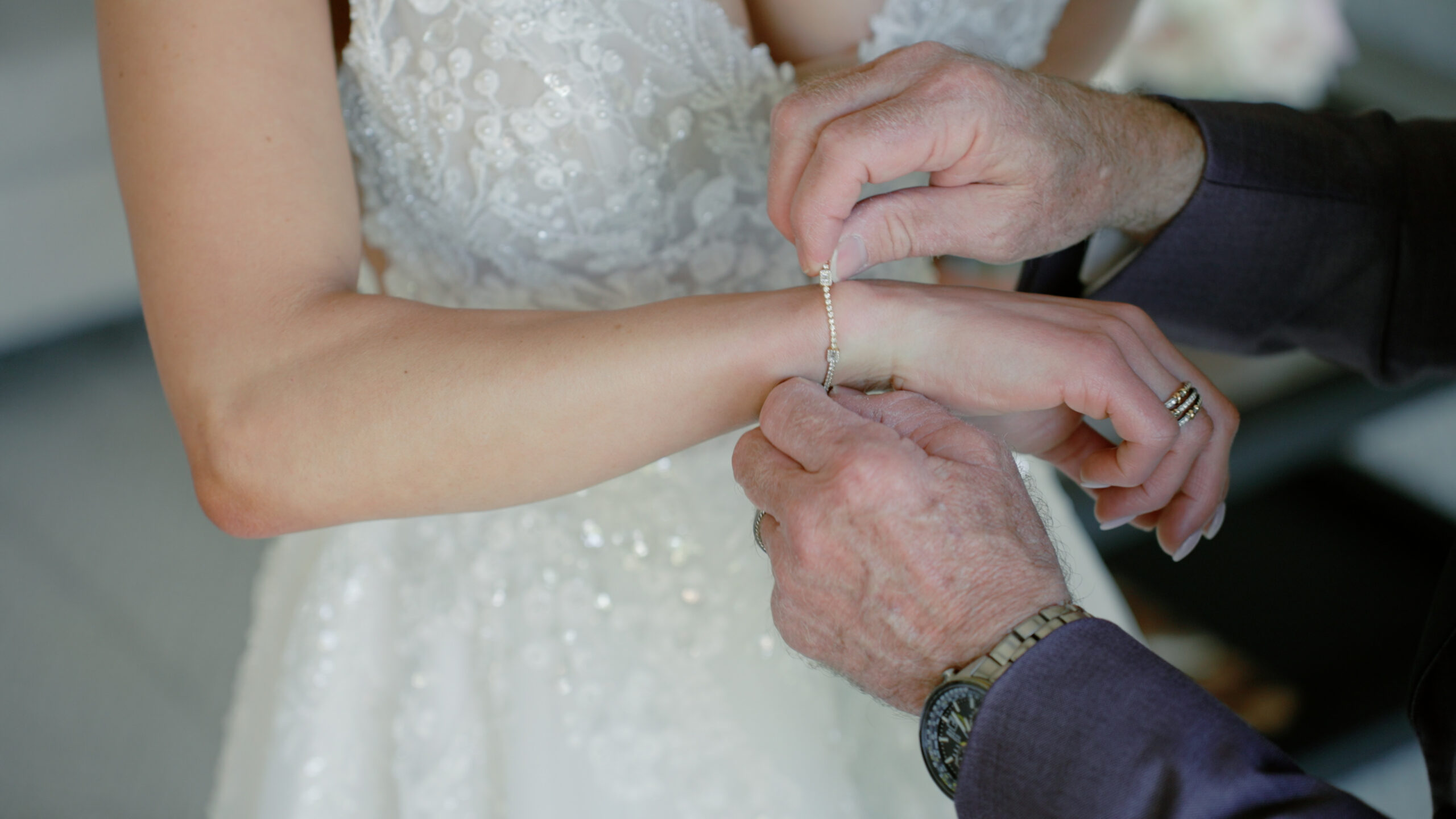 A tight shot of the father of the bride hooking a bracelet on his bride's wrist at her Dallas wedding.