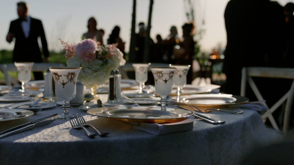 Tablescape set up at a wedding in Boston with guest silhouettes seen in the background.