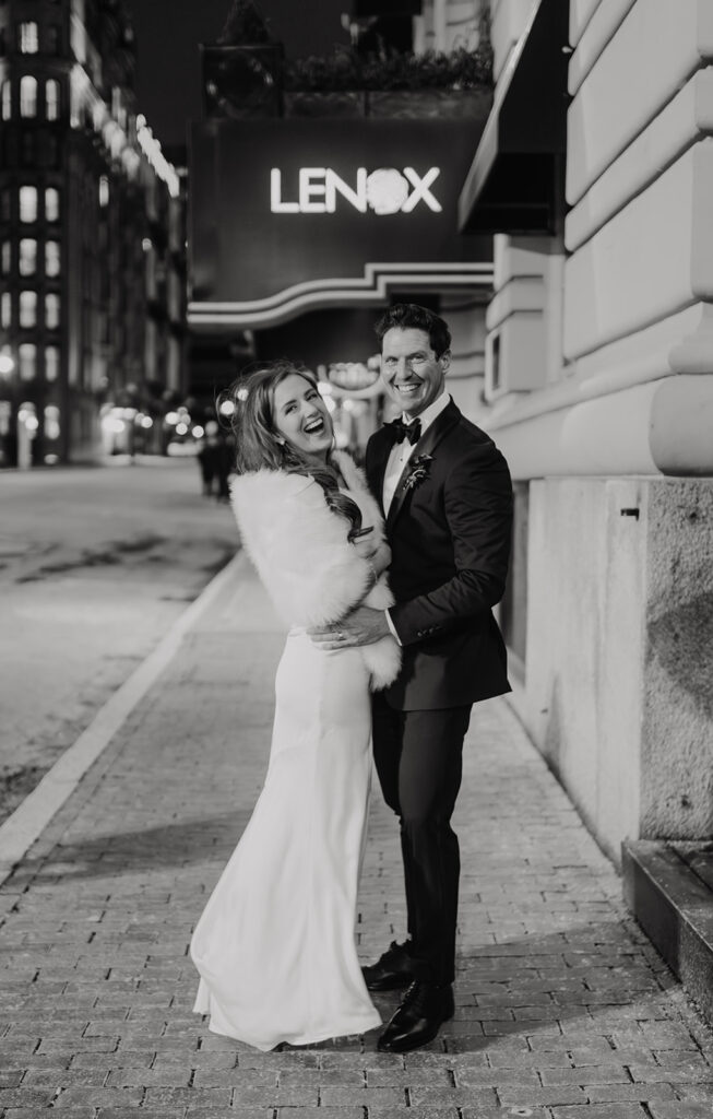 Bride and groom at the Lenox Hotel after their wedding, laughing in this black and white photo.