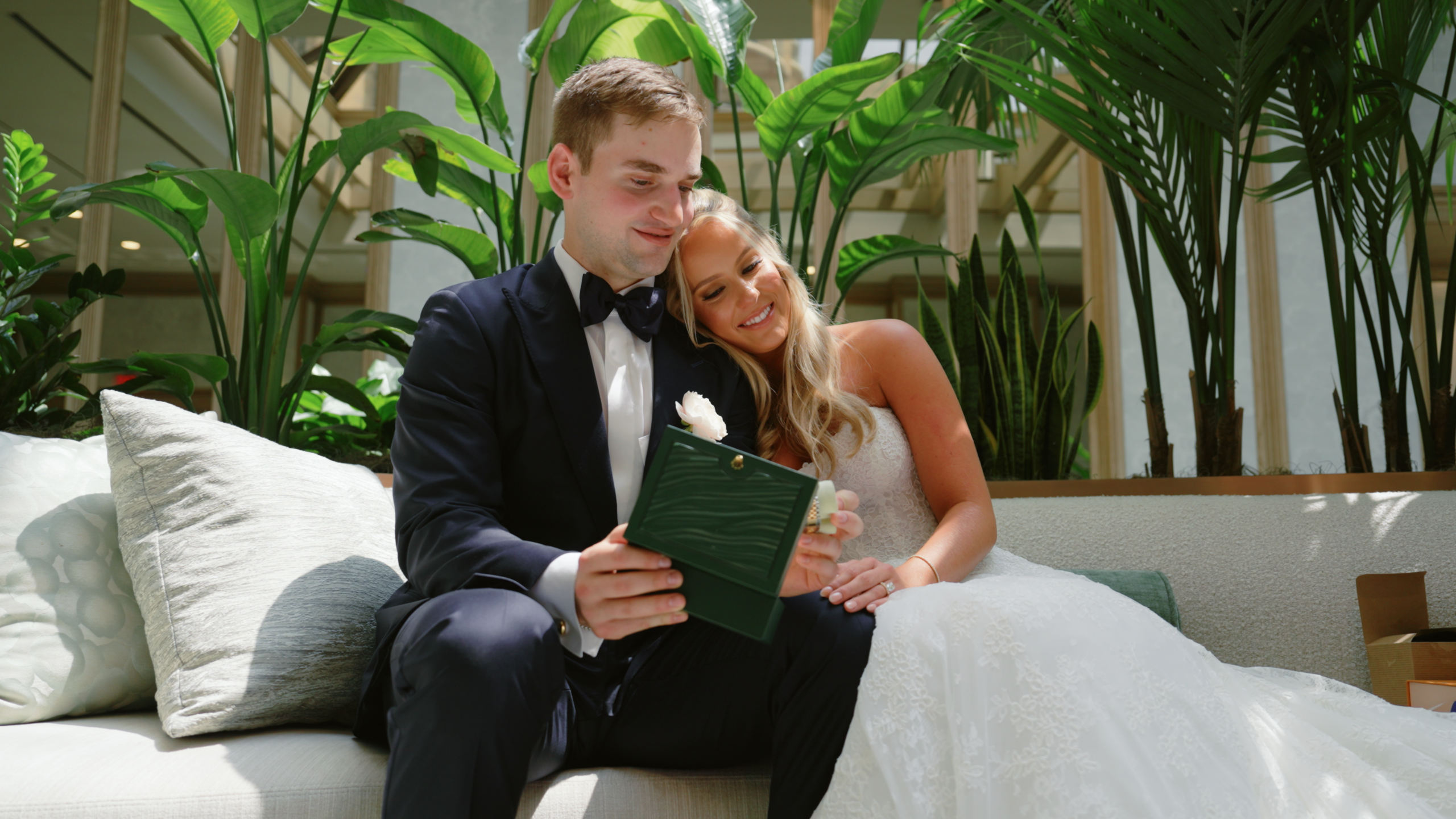 Newlyweds hugging on a couch with plants behind them in Dallas, TX.
