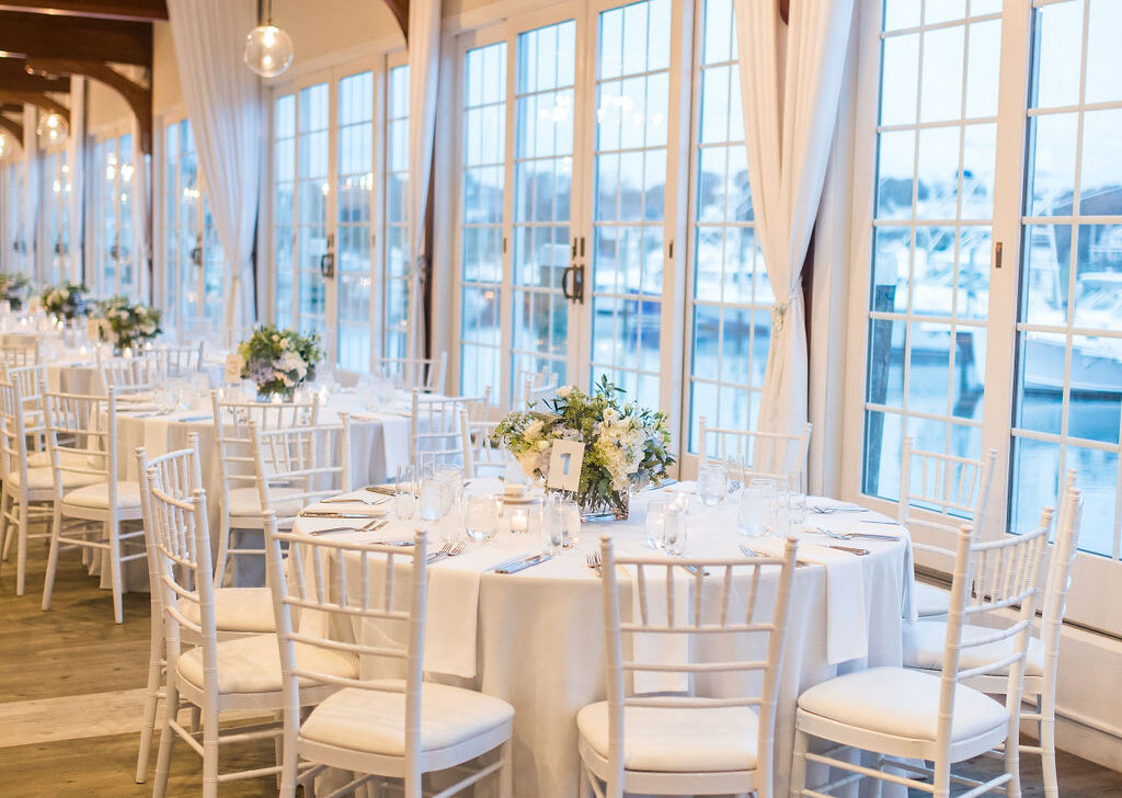Luxurious wedding reception tablescape inside Wychmere Beach Club with layered linens, floral centerpieces, and warm ambient lighting set for an upscale coastal celebration.