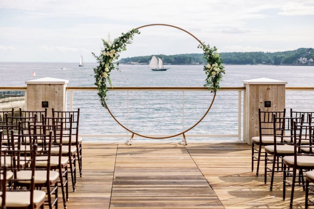 Exterior wedding ceremony setup at Beauport Hotel in Gloucester Massachusetts overlooking the ocean with coastal views, waterfront terrace, and elegant ceremony design along the North Shore.