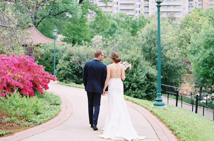 Bride and groom at Arlington Hall in Dallas, Texas, featuring a historic estate backdrop, elegant outdoor arrangements, and a romantic garden setting surrounded by manicured greenery.