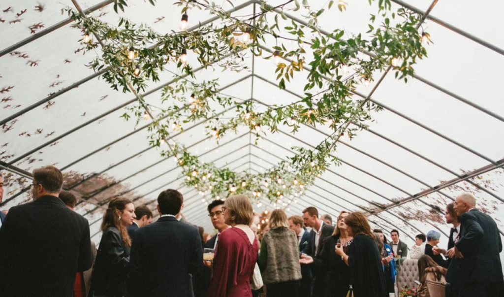Indoor wedding at Herb Lyceum with guests mingling in a greenhouse-style reception space.