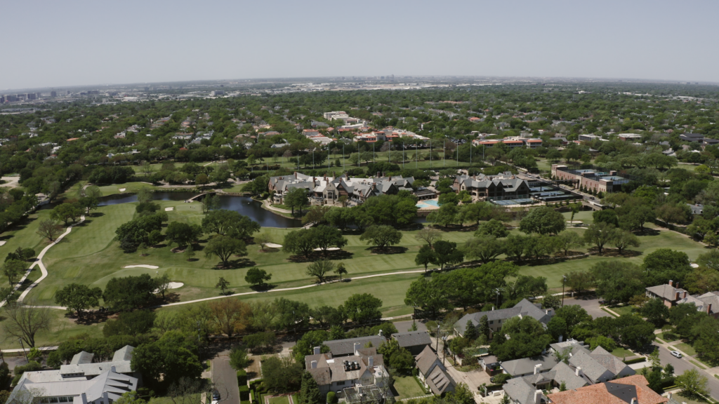 Aerial view of a sprawling wedding venue in Dallas, Texas, showcasing several acres of landscaped grounds, open green space, and elegant event buildings set within a scenic estate.