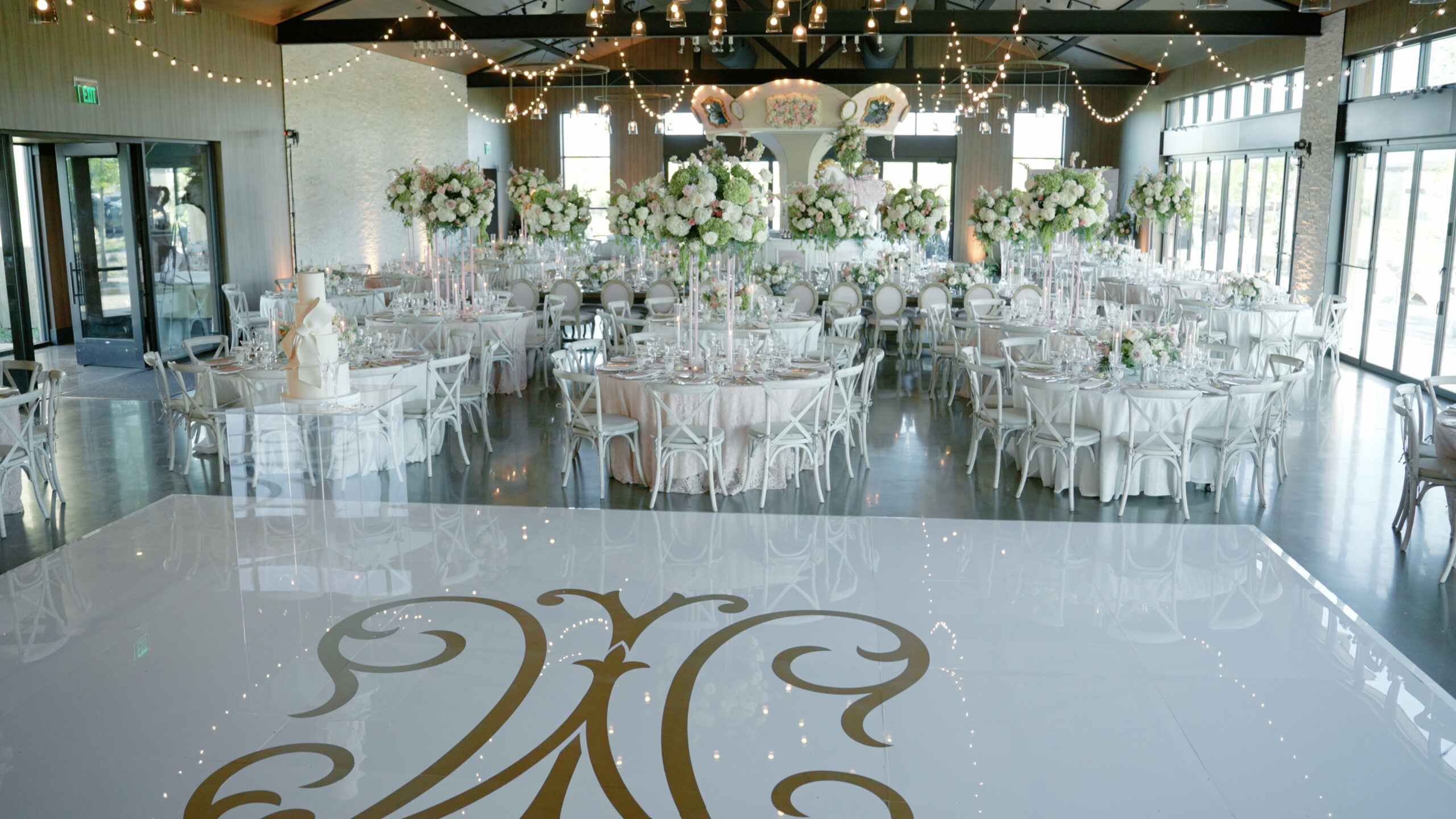 Interior of a wedding venue with a dance floor and ornate tables for the guests.