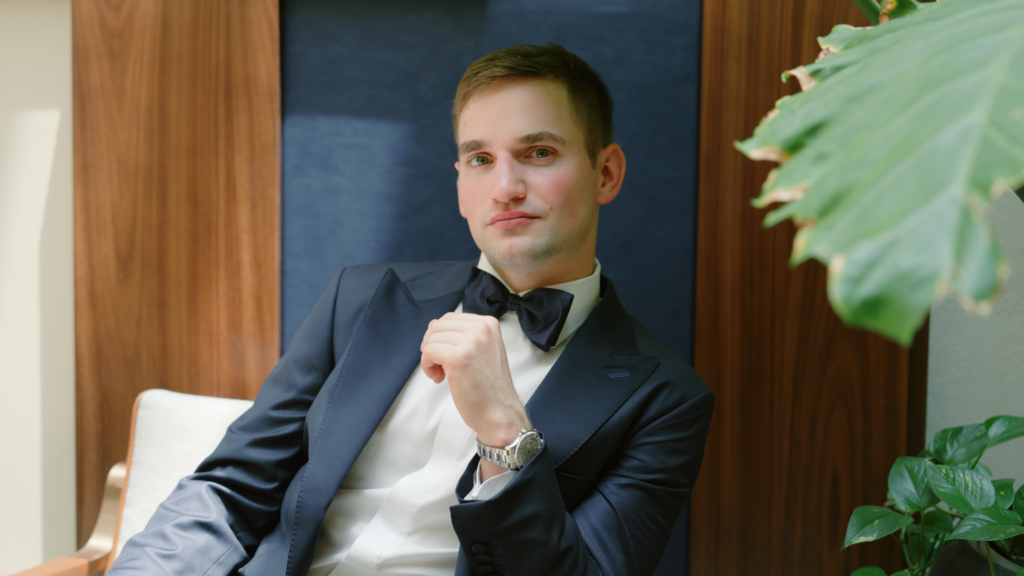 Groom seated at Bella Donna Chapel in McKinney, Texas, looking toward the camera in a calm, reflective moment captured inside the elegant ceremony space.