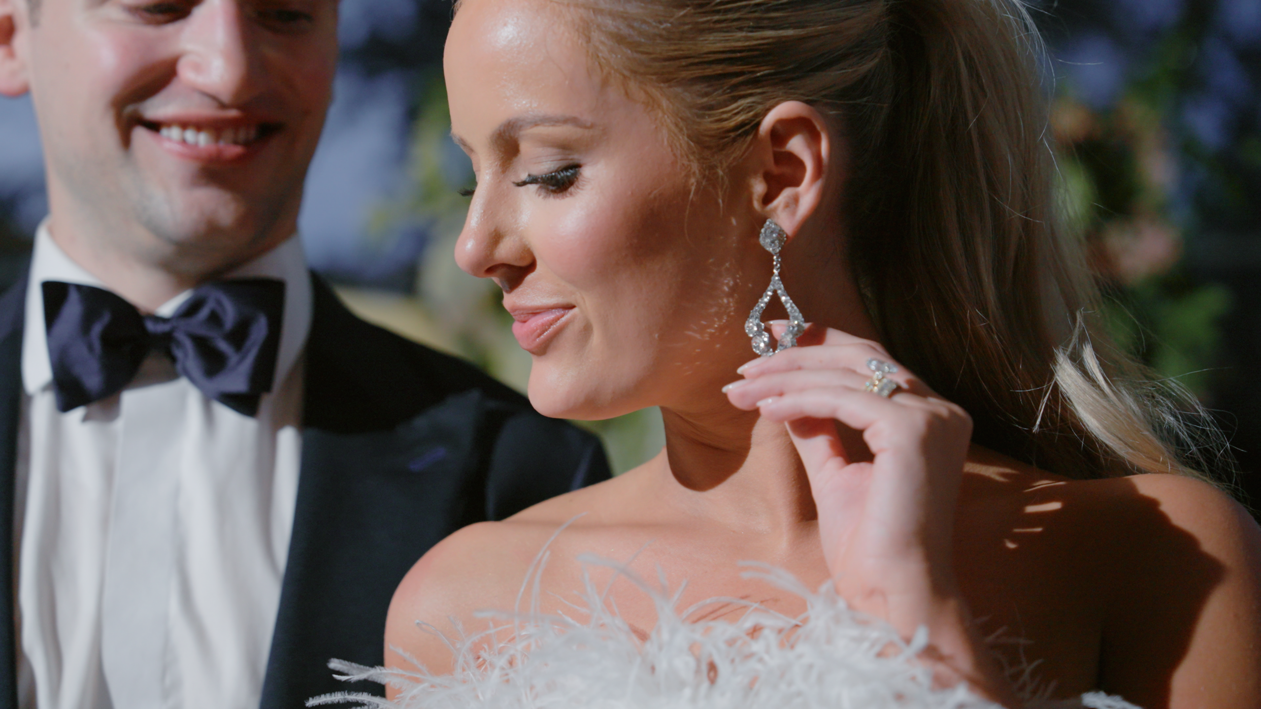 Bride holding her earring while her groom looks down at her during an intimate wedding moment.