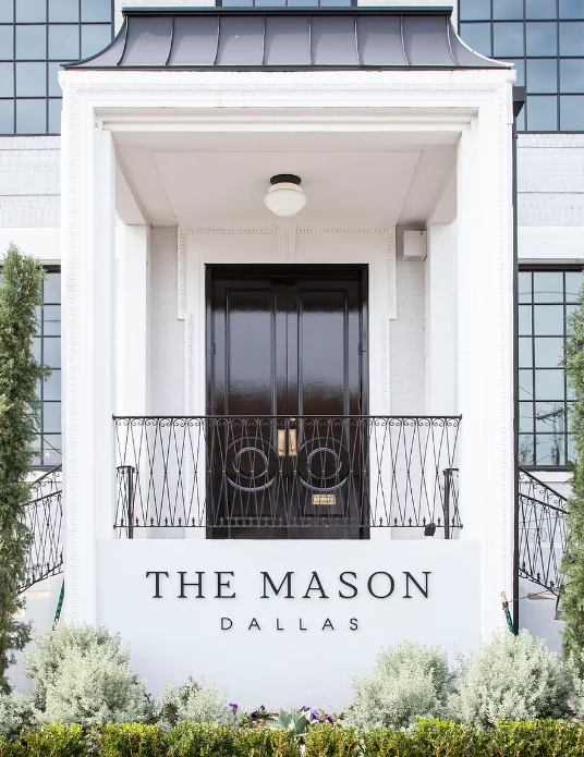 Exterior view of The Mason in Dallas, Texas, showcasing its historic brick facade, large windows, and urban industrial character in a downtown setting.