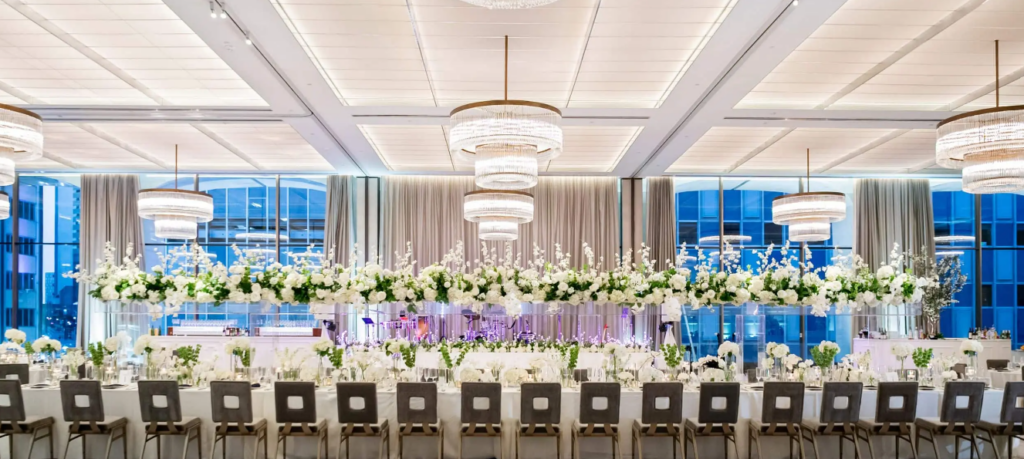 Reception table at Thompson Dallas adorned with large white floral arrangements, creating an elegant and modern wedding setting.