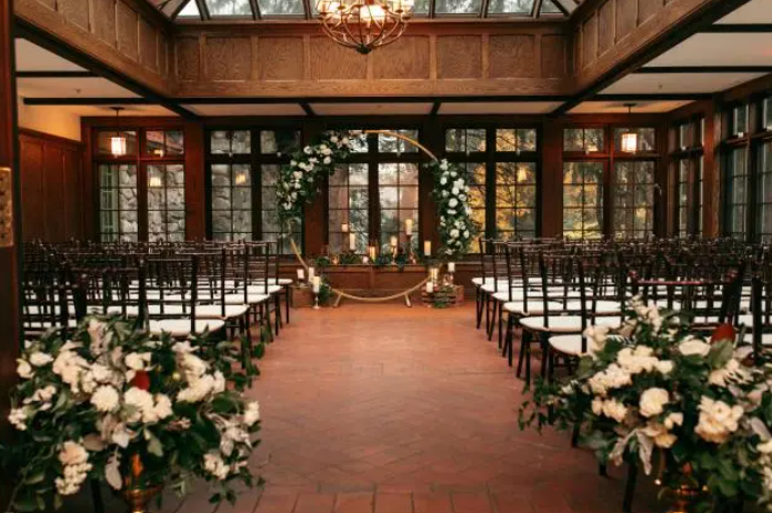 Wedding ceremony setup at Willowdale Estate featuring a romantic outdoor-inspired arrangement with lush greenery, elegant floral accents, and rows of seating framed by the historic estate architecture.
